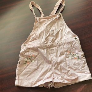 Blush colored overalls with floral pattern on pockets